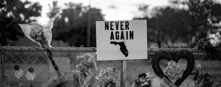 A Never Again sign hangs at a memorial for Marjory Stoneman Douglas High School.